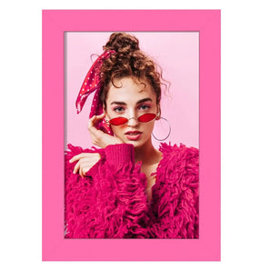 Portrait of woman in pink fuzzy sweater and red sunglasses in a vibrant pink photo frame