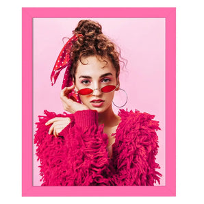 Portrait of a woman in a pink frame, red sunglasses, and textured pink sweater on pink background