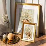 Gold framed custom floral wall art prints with woman's face, displayed in sunlit room