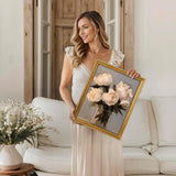 Woman holding a framed floral canvas print in a cozy living room setting