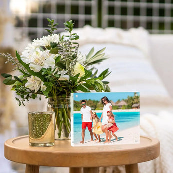Custom acrylic photo frame with family beach portrait on wooden table beside fresh flower bouquet