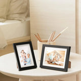 Two black photo frames with family pictures on a modern bedside table, cozy bedroom decor