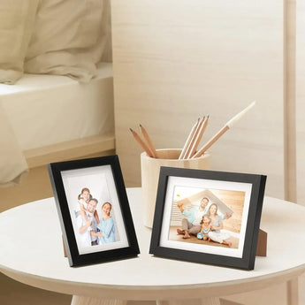 Two black photo frames with family pictures on a modern bedside table, cozy bedroom decor
