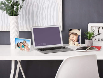 Modern workspace with custom photo frames, laptop, clock, and decorative plants on white desk