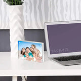Custom acrylic photo frame with happy family on modern white desk beside laptop and vase