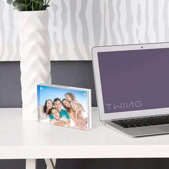 Custom acrylic photo frame with happy family on modern white desk beside laptop and vase