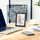 Black photo frame with family picture on modern desk with laptop and coffee cup
