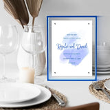 Custom blue acrylic frame displaying a wedding invitation on a modern dining table setup