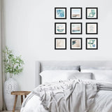 Modern bedroom with nine black-framed art prints and beach-inspired wall decor above bed