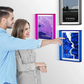 Smiling couple admiring colorful custom acrylic photo frames displayed on a white wall.
