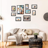 Gallery wall of custom picture frames above beige sofa with a dog in modern living room