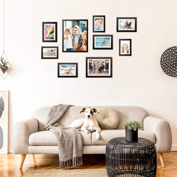 Gallery wall of custom picture frames above beige sofa with a dog in modern living room