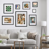 Modern living room with gray sofa, gallery wall of custom framed abstract and floral prints, and floor lamp