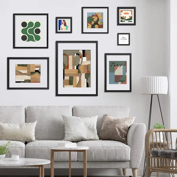 Modern living room with gray sofa, gallery wall of custom framed abstract and floral prints, and floor lamp