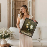 Woman in light dress holding framed floral art print in cozy living room