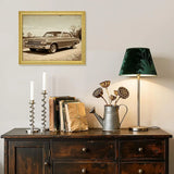 Vintage car wall art in gold frame above rustic sideboard with books, lamp, and decor