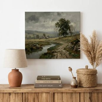 Framed landscape canvas print above rustic wooden console with lamp, books, and decor